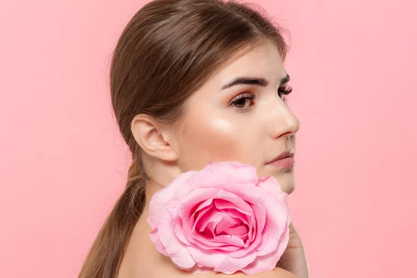 Retrato de cerca de una hermosa joven con rosa rosa aislada sobre fondo rosa . — Foto de Stock