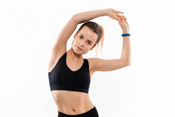 Joven mujer rubia deportiva en una ropa deportiva negro estiramiento antes de hacer ejercicio aislado sobre fondo blanco . — Foto de Stock