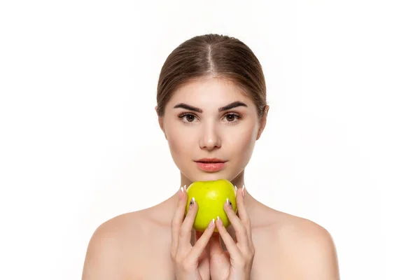 Крупный план портрет счастливой красивой молодой девушки, держащей зеленое яблоко близко к лицу на белом фоне . — стоковое фото