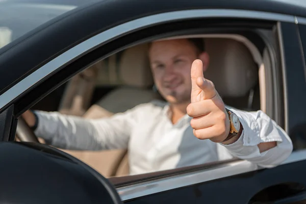 Porträt eines glücklichen Fahrers im weißen Hemd am Steuer seines Luxusautos. — Stockfoto