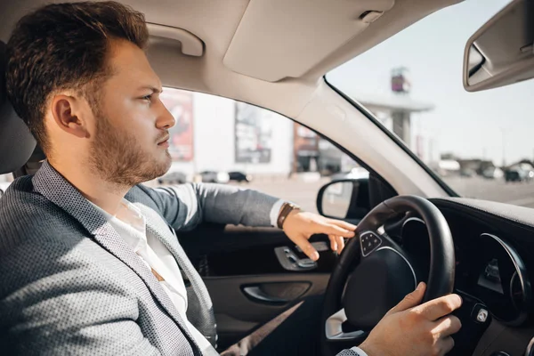 Takım elbiseli başarılı işadamı lüks arabasını kullanıyor.