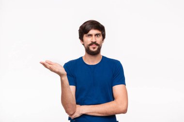 Mavi gömlekli yakışıklı brunet adam kollarını göğsüne katlanmış tutan ve beyaz arka plan üzerinde izole duran şüpheci duygu ile havada bir el atma.