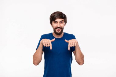 Sakallı mavi gömlekli yakışıklı brunet adam ve bıyıkları parmaklarıyla beyaz arka plan üzerinde izole ayakta işaret. Ürün ve reklam yeri.