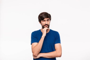 Mavi gömlekli yakışıklı brunet adam kollarını göğsüne katlanmış tutan ve beyaz arka plan üzerinde izole duran şüpheci duygu ile yüzüne yakın el tutmak.