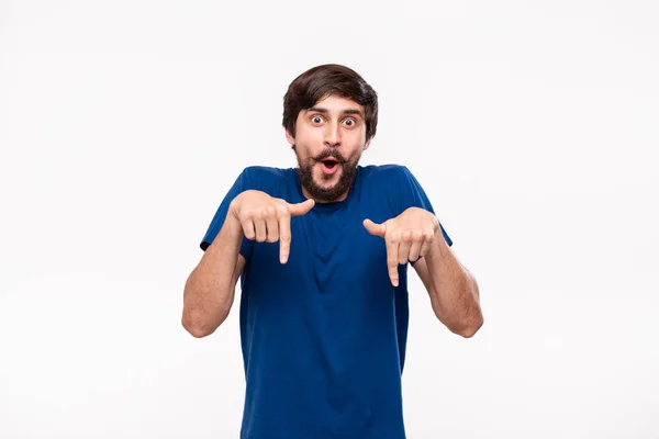 Bello uomo brunetta in camicia blu con barba e baffi puntando le dita in piedi isolato su sfondo bianco. Luogo del prodotto e della pubblicità . — Foto Stock