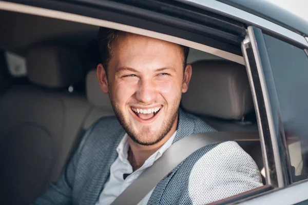 Retrato de un joven empresario sonriente en un traje en un asiento trasero — Foto de Stock