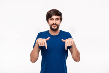Sakallı mavi gömlekli yakışıklı brunet adam ve bıyıkları parmaklarıyla beyaz arka plan üzerinde izole ayakta işaret.