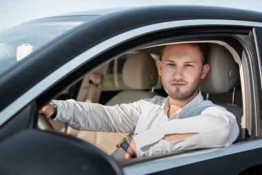 Beyaz gömlekli başarılı işadamı lüks arabasını kullanıyor.