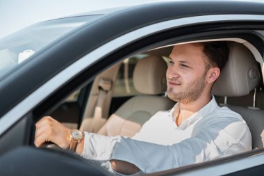 Beyaz gömlekli başarılı işadamı lüks arabasını kullanıyor.