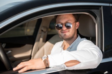 Beyaz gömlek ve güneş gözlüğü mutlu sürücü onun lüks araba sürücüleri.