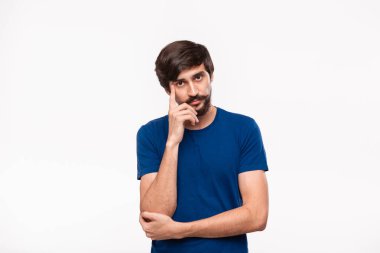 Mavi gömlekli düşünceli yakışıklı brunet adam kollarını göğsüne katlanmış tutan ve beyaz arka plan üzerinde izole ayakta yüz bir el yakın tutmak.