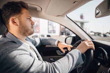 Takım elbiseli başarılı işadamı lüks arabasını kullanıyor.