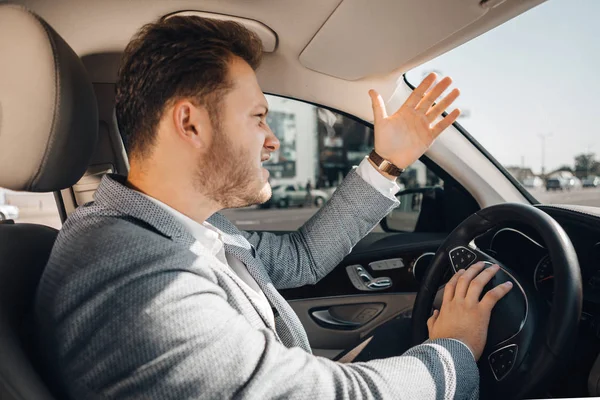 Conductor enojado en un atasco de tráfico perdiendo su manipulador y haciendo un gesto para dejar ir su coche. Llegar tarde — Foto de Stock