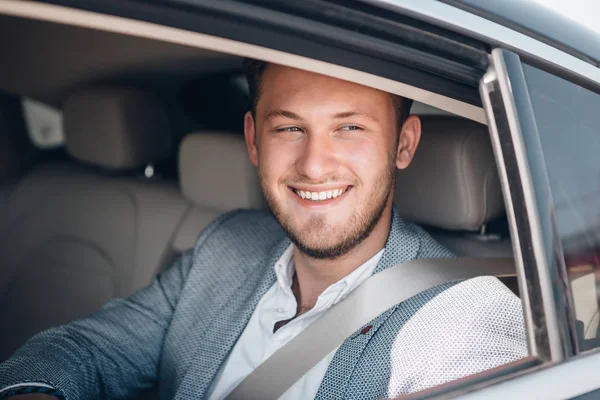 Retrato de un joven empresario feliz en un traje en un asiento trasero — Foto de Stock