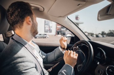 Lüks arabasında dans eden takım elbiseli mutlu sürücü müzik dinleyip hayatın tadını çıkarıyor.