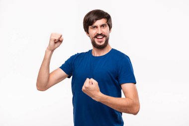 Mavi gömlek bıyıklı genç brunet sakallı adam kollarını beyaz arka plan üzerinde izole duran zafer jest ifade poz.