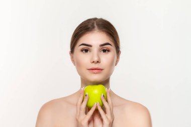 Beyaz arka plan üzerinde izole yüz yakın yeşil elma tutan mutlu bir güzel genç kız yakın çekim portre.