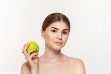 Beyaz arka plan üzerinde izole yüz yakın yeşil elma tutan mutlu bir güzel genç kız yakın çekim portre.