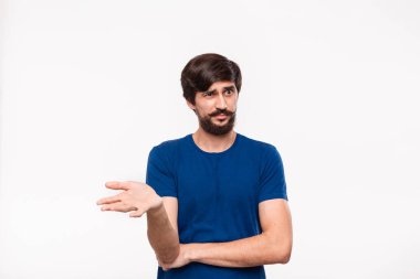 Mavi gömlekli yakışıklı sakallı brunet adam kollarını göğsüne katlanmış tutan ve şüpheci duygu ile havada bir el atma beyaz arka plan üzerinde izole ayakta.