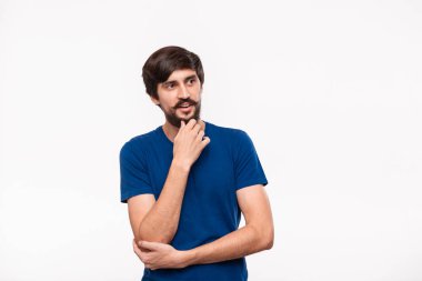 Mavi gömlekli düşünceli yakışıklı brunet adam kollarını göğsüne katlanmış tutan ve beyaz arka plan üzerinde izole ayakta yüz bir el yakın tutmak.