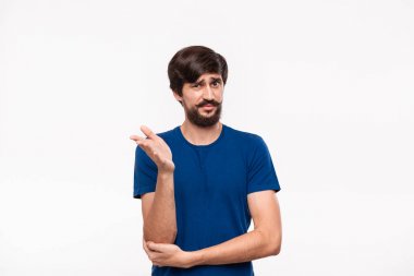 Mavi gömlekli yakışıklı sakallı brunet adam kollarını göğsüne katlanmış tutan ve şüpheci duygu ile havada bir el atma beyaz arka plan üzerinde izole ayakta.