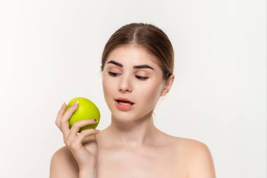 Beyaz arka plan üzerinde izole yüz yakın yeşil elma tutan mutlu bir güzel genç kız yakın çekim portre.