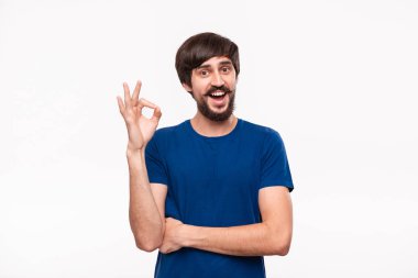 Beyaz arka plan üzerinde izole duran Ok işareti jest gösteren mavi gömlek bıyıklı yakışıklı brunet sakallı adam.