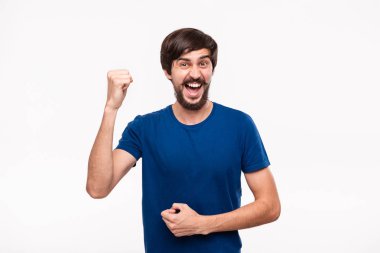Mavi gömlek bıyıklı genç brunet sakallı adam kollarını beyaz arka plan üzerinde izole duran zafer jest ifade poz.