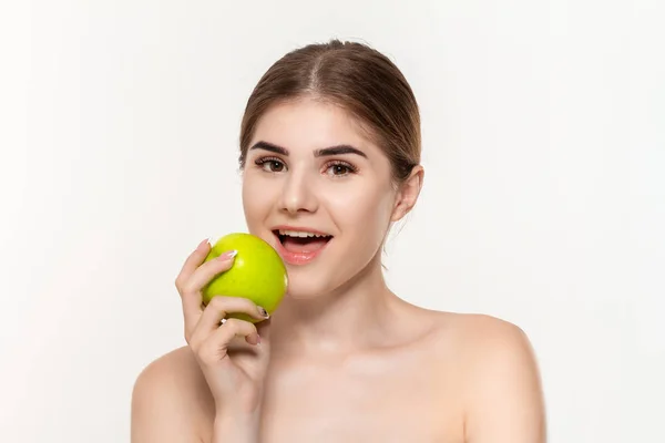 Крупный план портрета счастливой молодой девушки, кусающей зеленое яблоко на белом фоне. Концепция красоты и здравоохранения . — стоковое фото