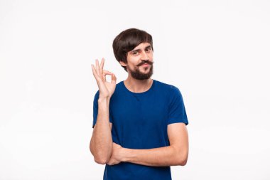 Beyaz arka plan üzerinde izole duran Ok işareti jest gösteren mavi gömlek bıyıklı yakışıklı brunet sakallı adam.