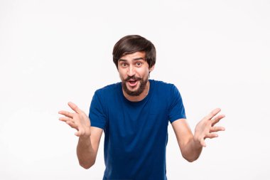 Sakallı mavi gömlekli yakışıklı brunet adam ve çoğu beyaz arka plan üzerinde izole duran her iki eliyle şans duygu ifade. Duygu ve olumlu sürpriz jest.