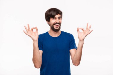 Yakışıklı brunet sakallı adam mavi gömlek bıyıklı ok işareti gösteren iki eli beyaz arka plan üzerinde izole ayakta. Tamam hareketi.
