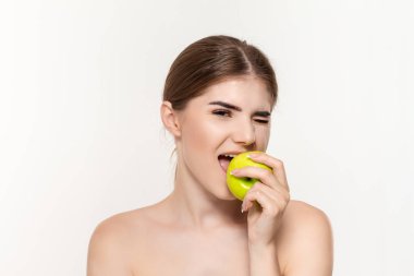 Beyaz arka plan üzerinde izole yeşil elma ısırma mutlu bir güzel genç kız yakın çekim portre. Güzellik ve sağlık kavramı.