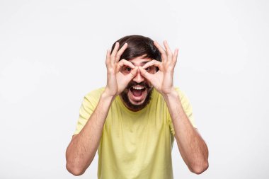 Yakışıklı brunet sakallı adam sarı gömlek bıyıklı ok işareti gösteren iki eli beyaz arka plan üzerinde izole ayakta. Tamam hareketi.