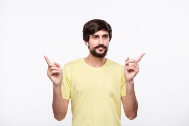 Bıyıklı sarı tişörtlü Pretty brunet sakallı adam beyaz arka plan üzerinde izole kablosuz kulak tomurcukları ile müzik dinleme şarkıları zevk.