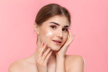 Güzel model pembe arka plan üzerinde izole bir hyaluronik krem beyaz tüp tutan cilde nemlendirici kozmetik ürün uygular. Güzellik ve sağlık tedavisi kavramı.