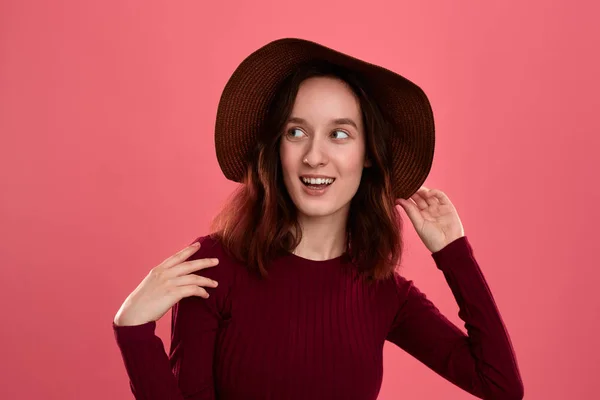 Retrato de una hermosa chica morena feliz en un sombrero de ala ancha posando sobre un fondo rosa oscuro . —  Fotos de Stock