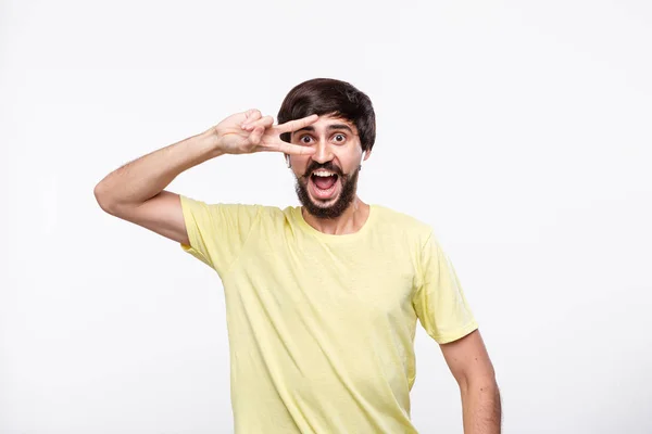 Upphetsad Brunet skäggiga man i en gul t-shirt med mustascher njuter musik lyssnar låtar med trådlösa hörlurar och dansa isolerade över vit bakgrund. — Stockfoto