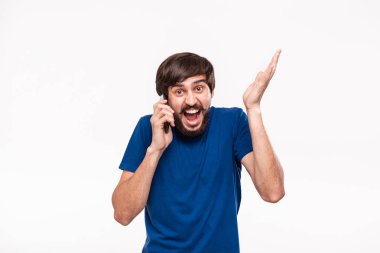 Sakallı mavi gömlekli pretty brunet adam ve çoğu ağrıları beyaz arka plan üzerinde izole duran kamera bakarak akıllı telefon tutarak şok. Sürpriz duygu.