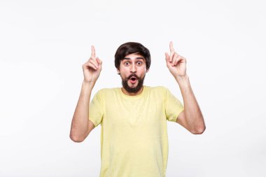 Sakallı sarı gömlekli yakışıklı brunet adam ve bıyıkları parmaklarıyla beyaz arka plan üzerinde izole ayakta işaret. Ürün ve reklam yeri.