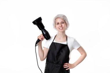 Beyaz tee ve siyah önlük profesyonel siyah saç kurutma makinesi beyaz arka plan izole iş için hazır tutan genç güzel kuaför. Sağlıklı yaşam endüstrisi ve profesyonel kariyer. Profesyonellere güvenin.