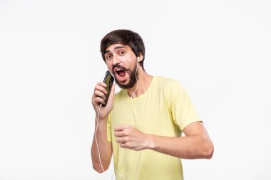 Sarı bir t-shirt şarkı ve dans spartphone ve kablolu kulaklık ile müzik zevk bıyıklı Yakışıklı brunet sakallı adam.
