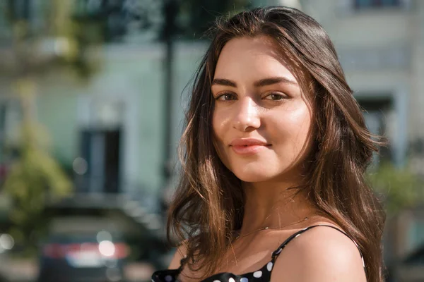 Beautiful young brunette woman dressed in a black dress rests during warm summer traveling in foreign countries.