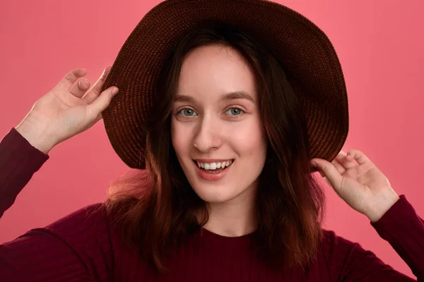 Retrato de cerca de una hermosa chica morena feliz con un sombrero de ala ancha posando sobre un fondo rosa oscuro . —  Fotos de Stock