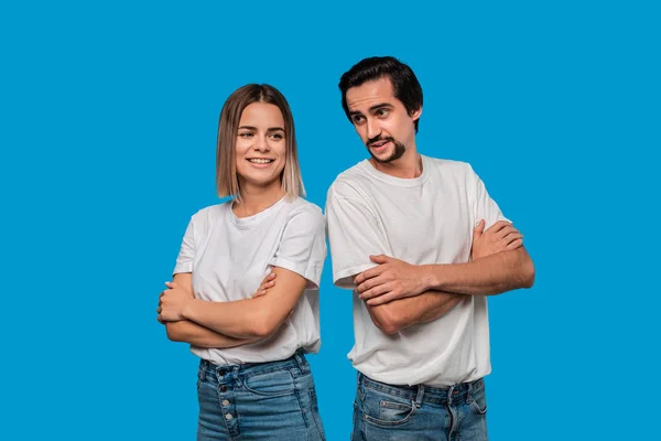 Beyaz t-shirt ve mavi kot mavi arka plan üzerinde izole ayakta bıyıklı genç bir sarışın kadın ve brunet sakallı adam Çift. — Stok fotoğraf
