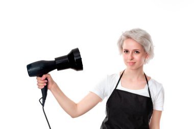 Beyaz tee ve siyah önlük profesyonel siyah saç kurutma makinesi tutan genç güzel kuaför saçlarını fan kendini yönetti. Sağlıklı yaşam ve güzellik endüstrisi ve profesyonel kariyer.