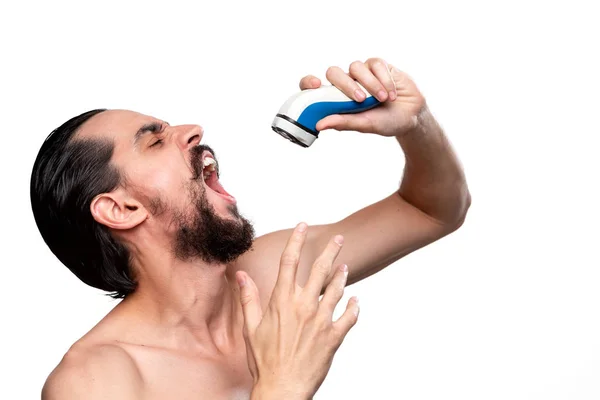 Hombre barbudo feliz con bigote utiliza afeitadora eléctrica como un micrófono cantando de pie desnudo aislado sobre fondo blanco. Disfrutar de la rutina de la mañana y afeitarse . — Foto de Stock