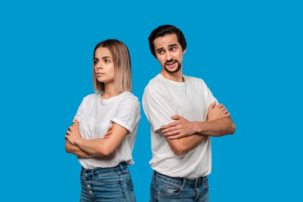 Pareja pensativa de un hombre morena barbuda con bigote y mujer rubia en camisetas blancas y pantalones vaqueros azules de pie aislado sobre fondo blanco . — Foto de Stock