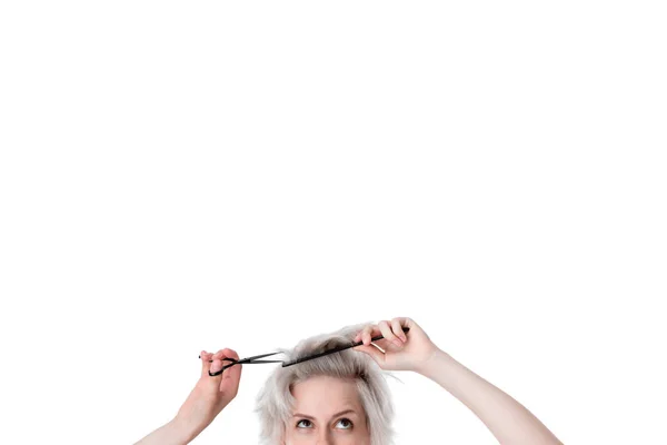 Close-up photo of a pretty young blond hairdresser cutting hair herself expressing emotion of  doubt. Beauty industry and professional career. Trust professional hairdressers. Copy space in upper side — Stock Photo, Image