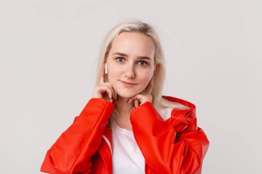 Kırmızı yağmurluk ve beyaz t-shirt giyen pretty sarışın kız kablosuz kulaklıkile müzik dinlerken dans. Hayattan zevk alanın.